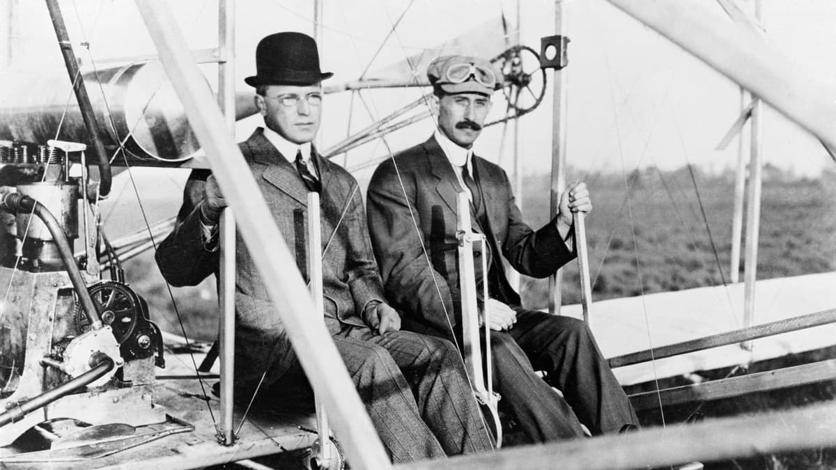 Wilbur and Orville Wright standing proudly with their aircraft at Kitty Hawk